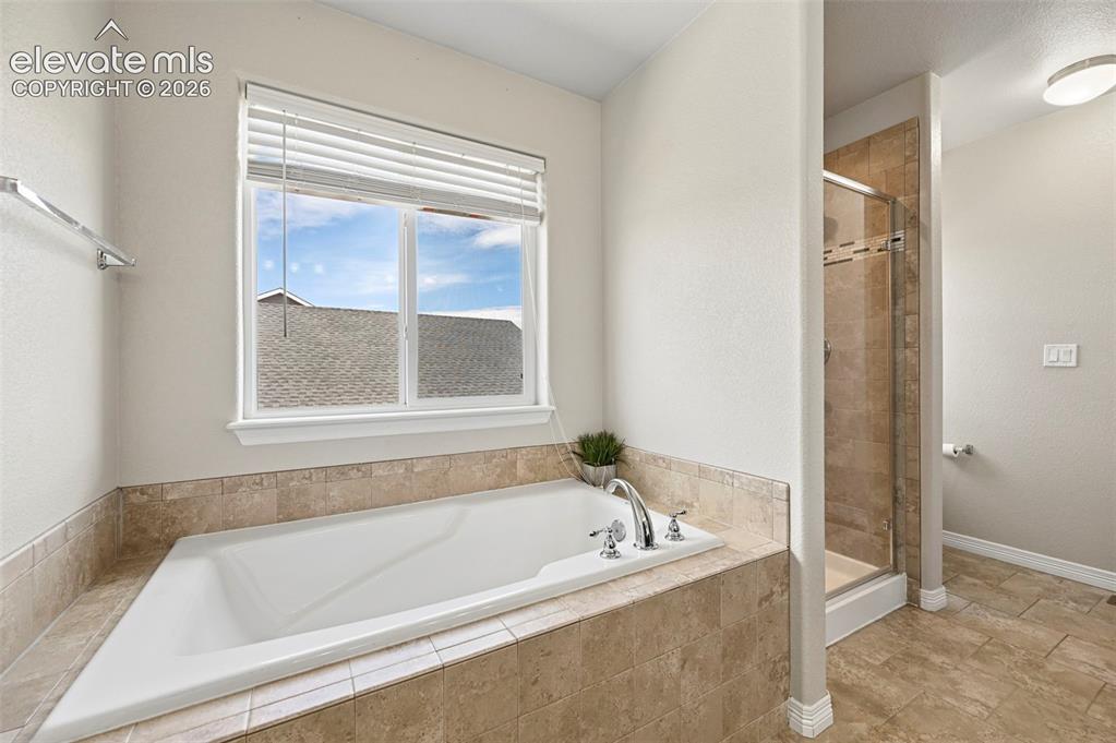 Image 14 of 29: Built-in soaking tub with polished chrome fixtures, surrounded by neutral-t