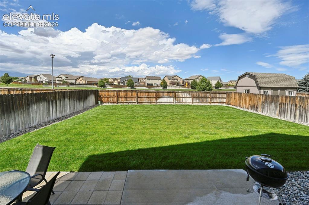 Image 22 of 29: Expansive backyard featuring a manicured lawn, wood fencing, and a concrete