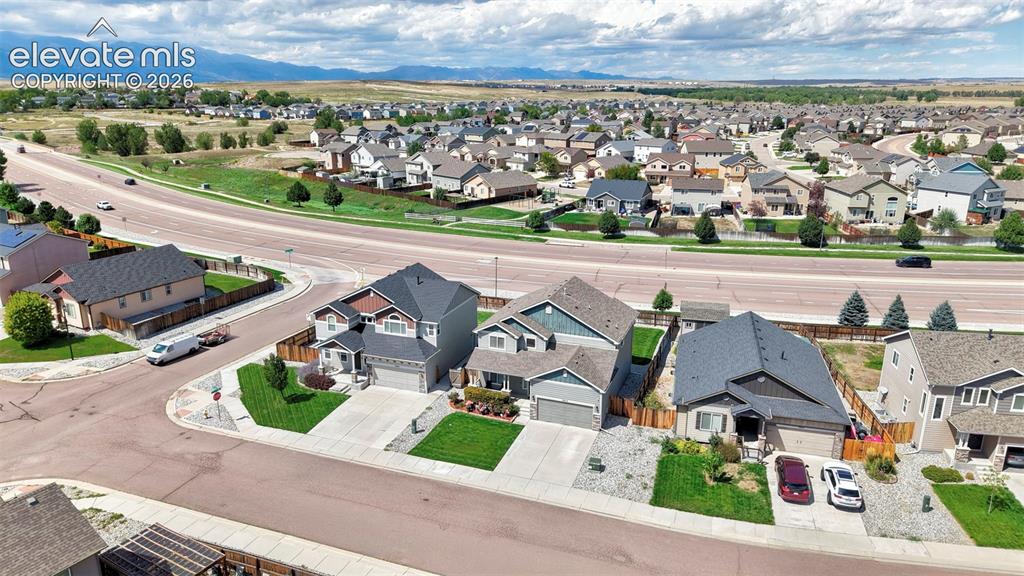 Image 26 of 29: Residential neighborhood with paved roads, manicured lawns, and visible mou