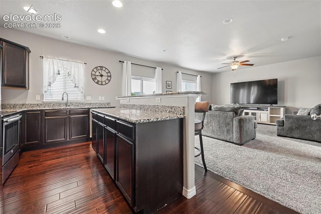 Image 3 of 29: Kitchen featuring dark wood cabinetry, granite countertops, and wood-finish