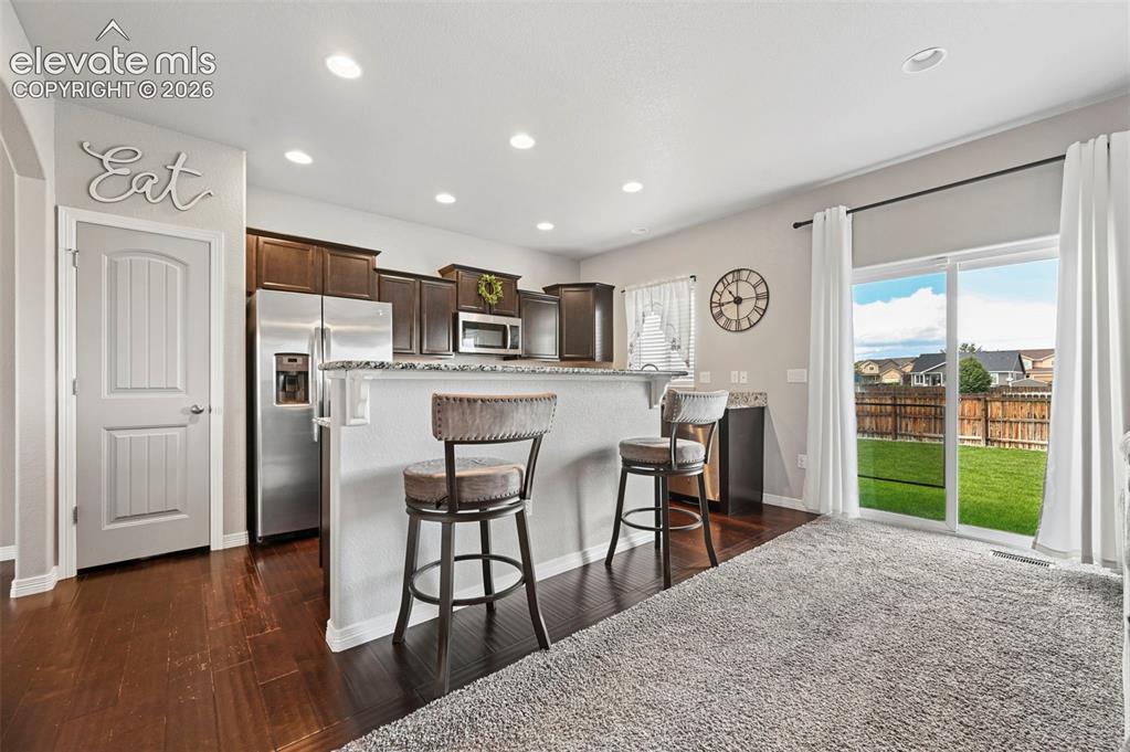 Image 4 of 29: Kitchen featuring dark wood cabinetry, stainless steel appliances, and a br