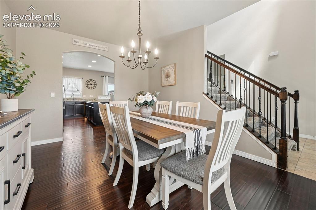 Image 6 of 29: Rich wood-finish flooring, staircase with wrought iron balusters, arched en