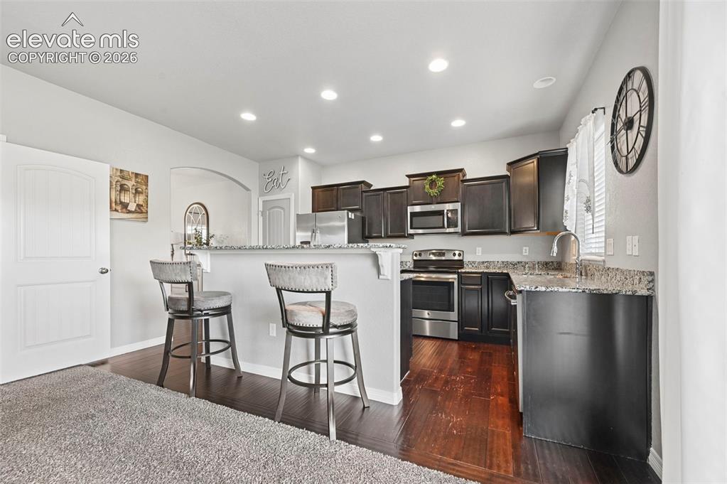 Image 7 of 29: Kitchen featuring dark wood-finish cabinetry, stainless steel appliances, s