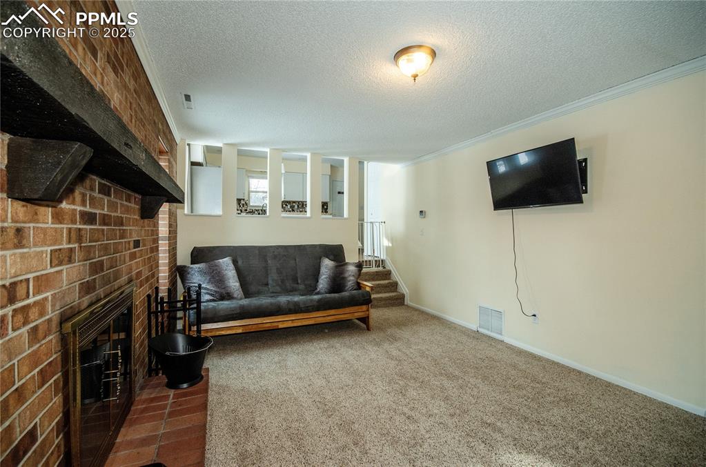 Image 10 of 23: Carpeted living room featuring a fireplace, a textured ceiling, and ornamen
