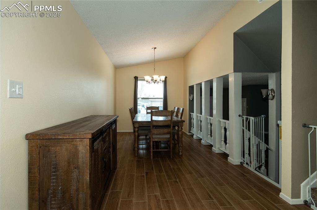 Image 5 of 23: Dining room with wood tiled floors, a chandelier, and lofted ceiling