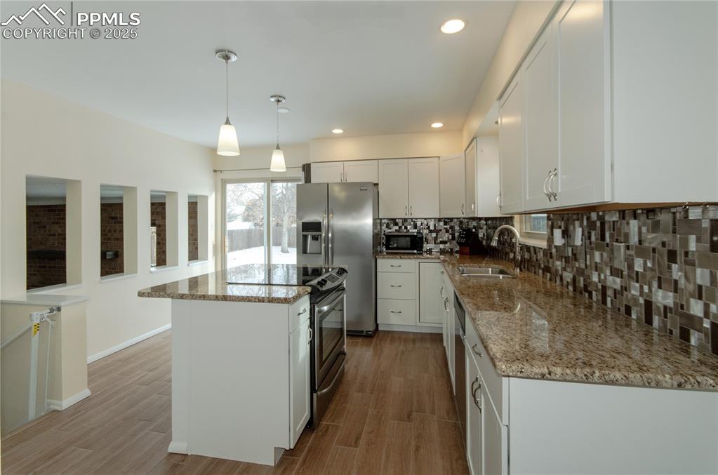 Image 6 of 23: Kitchen featuring white cabinetry, decorative backsplash, recessed lighting