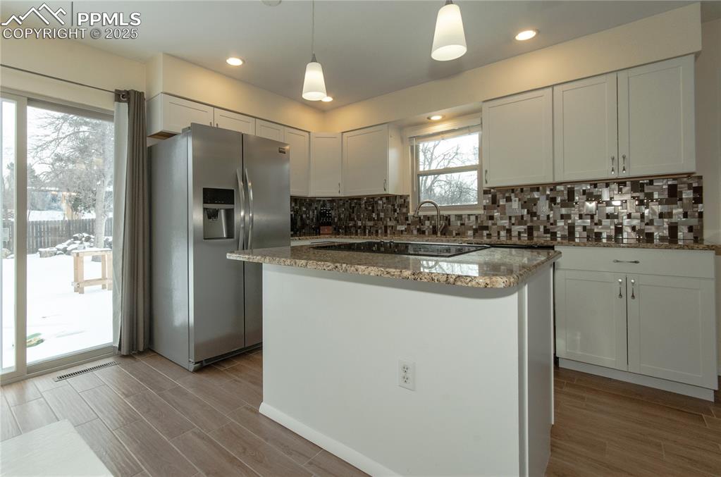 Image 7 of 23: Kitchen with stainless steel refrigerator with ice dispenser, wood tiled fl