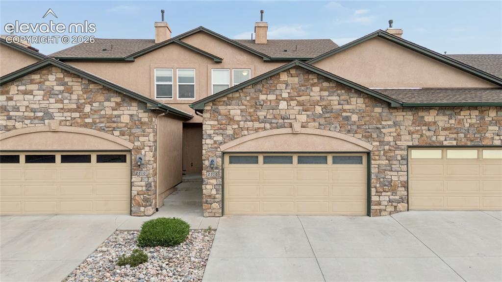 Caption: Stacked stone and stucco exterior featuring multiple garage bays with arched details and integrated 
