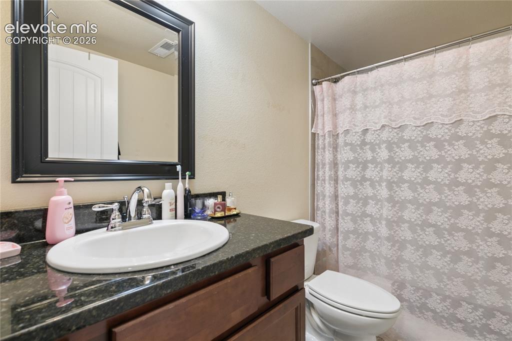 Image 16 of 28: Bathroom featuring a dark wood vanity with a dark speckled countertop, an u