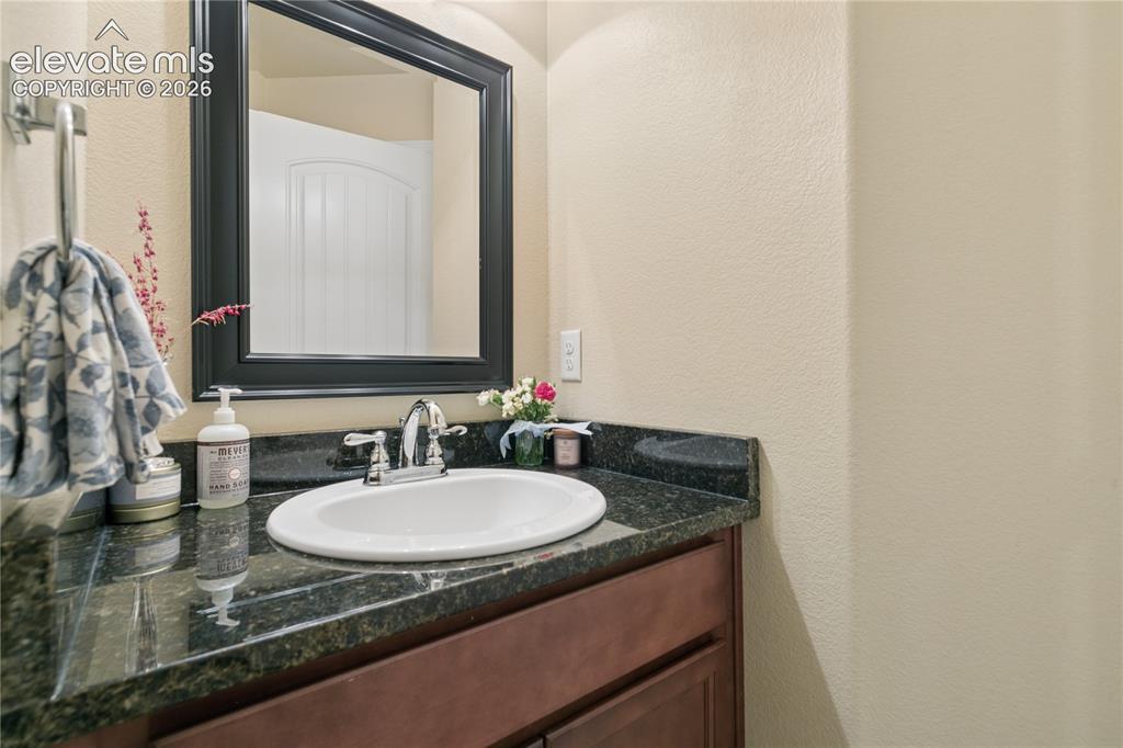 Image 18 of 28: Vanity featuring a dark stone countertop, undermount sink, and chrome fauce