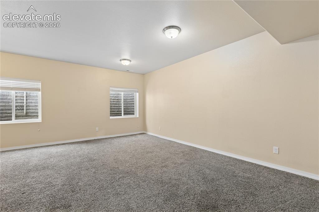Image 21 of 28: Spacious room featuring neutral wall paint, gray carpeting, dual windows wi