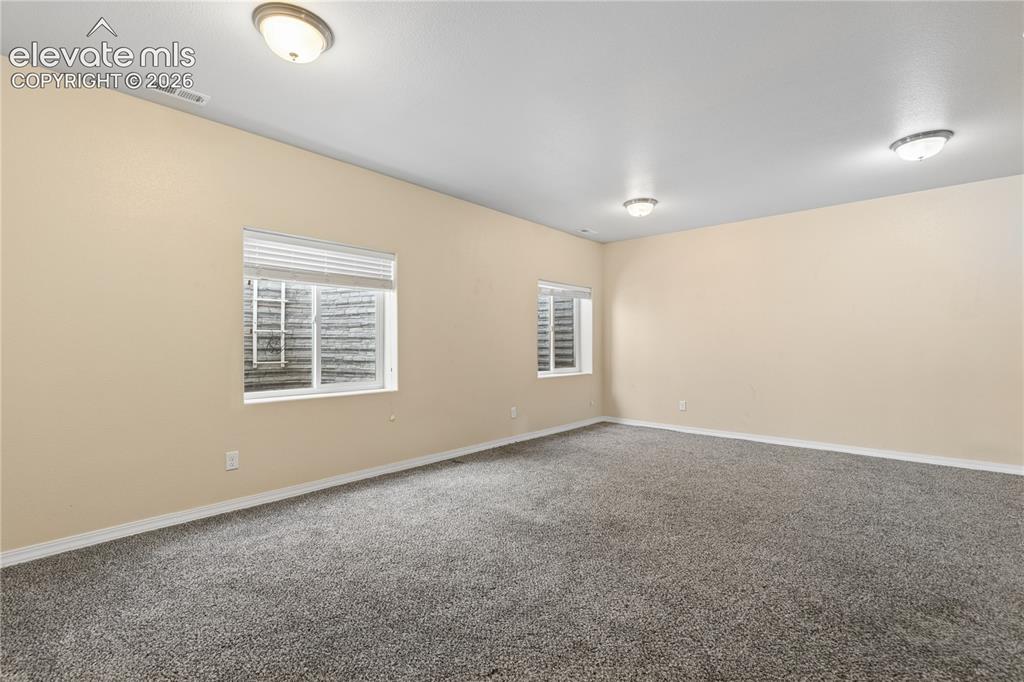 Image 26 of 28: Expansive room featuring neutral wall tones, gray carpeting, and multiple c