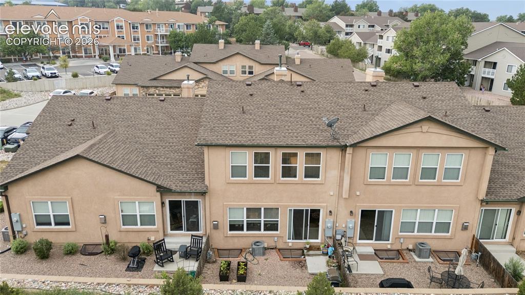 Image 27 of 28: Rear exterior of multi-level townhome featuring a stucco facade and a shing