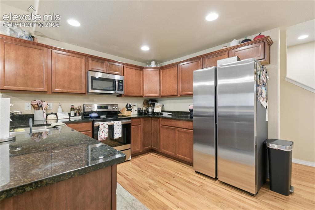 Image 3 of 28: Kitchen featuring wood-finish flooring, dark stone countertops, wood cabine