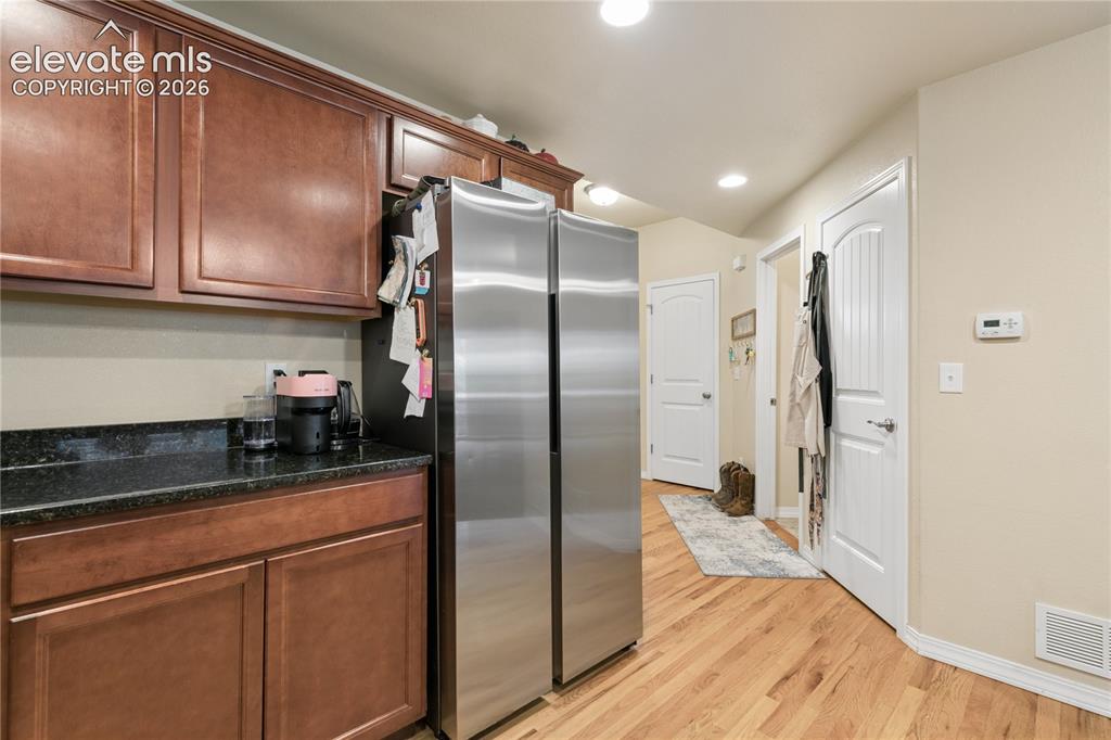 Image 4 of 28: Kitchen area featuring wood-finish cabinetry, dark countertop, and a stainl