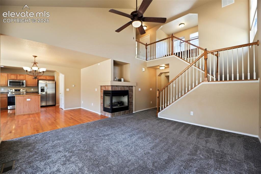 Image 10 of 47: Spacious living area featuring vaulted ceiling, a corner gas fireplace with