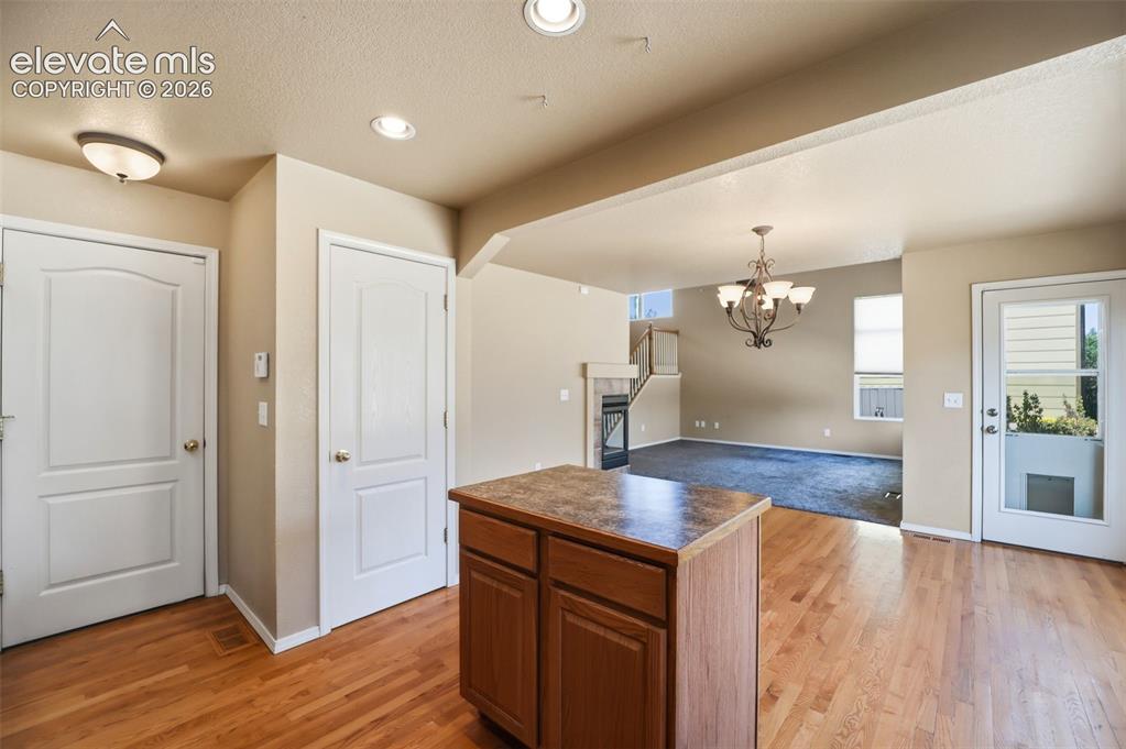 Image 18 of 47: Wood flooring throughout the kitchen and dining area, featuring a central i