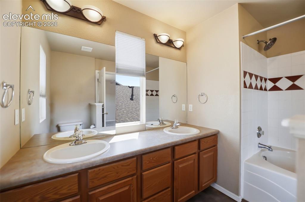 Image 24 of 47: Bathroom featuring a double vanity with wood cabinetry, integrated sinks, a