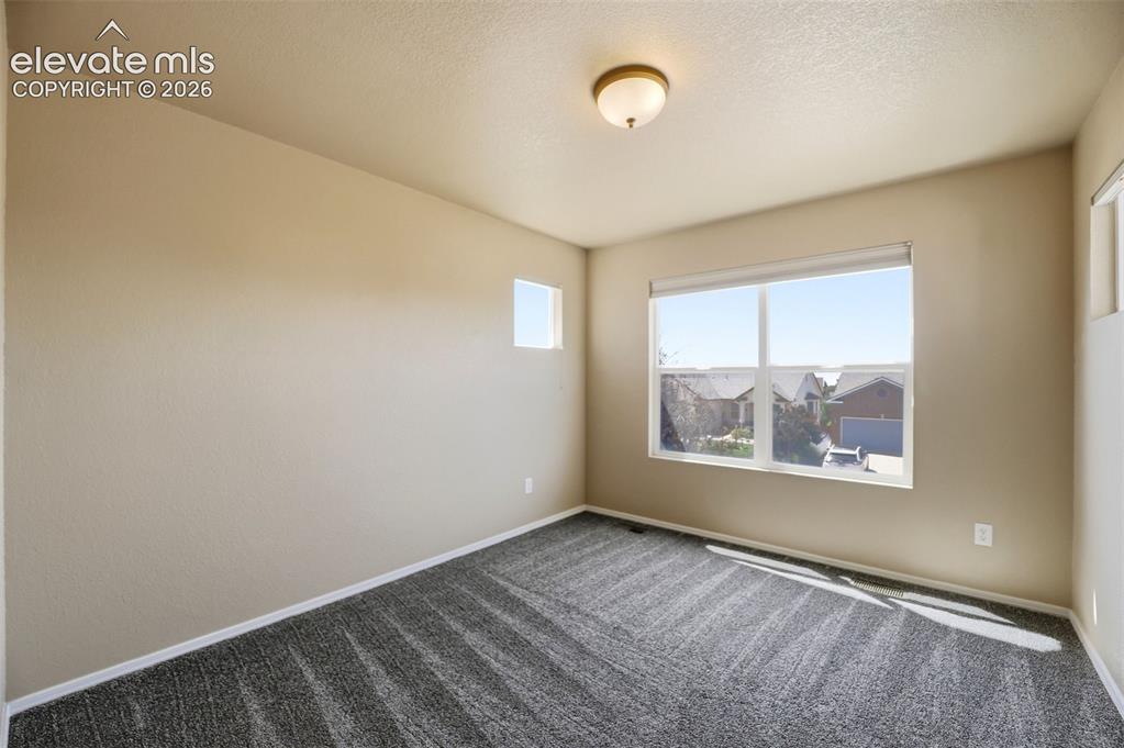 Image 27 of 47: Spacious interior featuring a large window with roller shades, neutral-tone