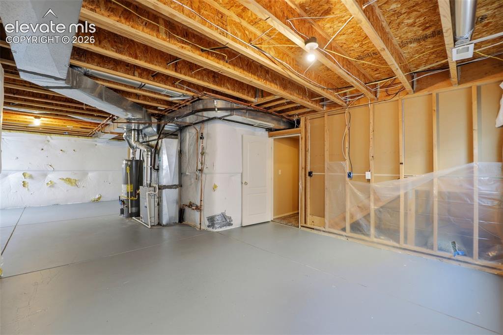 Image 31 of 47: Unfinished basement space featuring exposed wooden joists, painted concrete