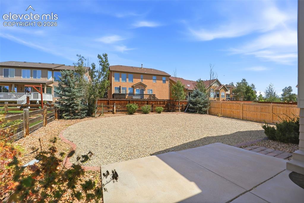 Image 32 of 47: Spacious backyard featuring a large gravel area, a concrete patio, and a wo