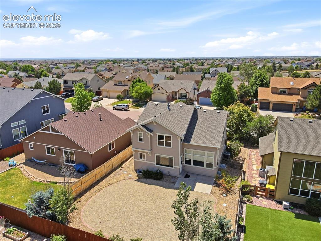Image 44 of 47: Expansive backyard featuring a large gravel patio, mature trees, and a wood
