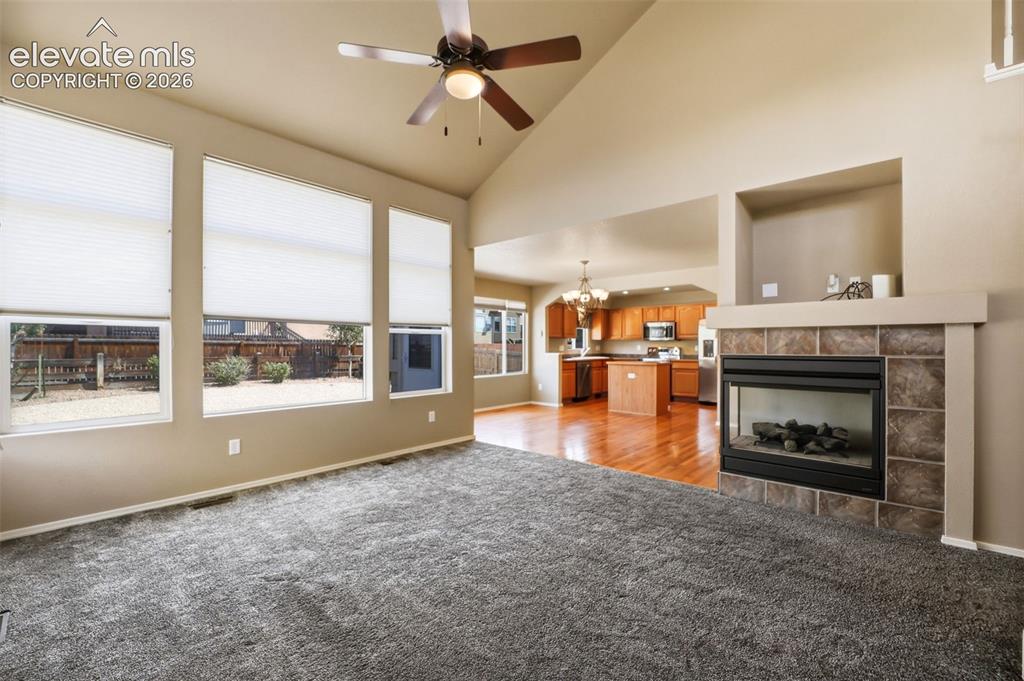 Image 9 of 47: Open concept living area featuring vaulted ceilings and a gas fireplace wit