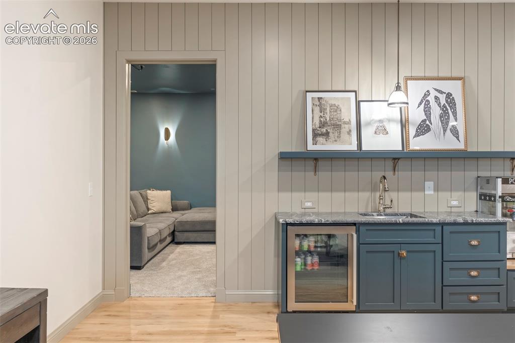 Image 35 of 49: Lower level kitchenette featuring custom cabinetry, open shelving, and a bu