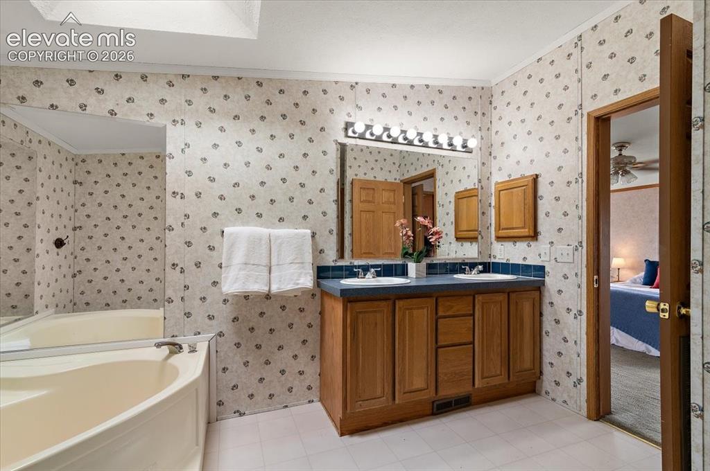 Image 10 of 23: Dual vanity with integrated sinks and wood-finish cabinetry, above-mirror l
