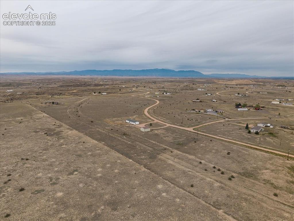 Image 19 of 23: Expansive land parcel featuring existing dirt roads and a distant mountain