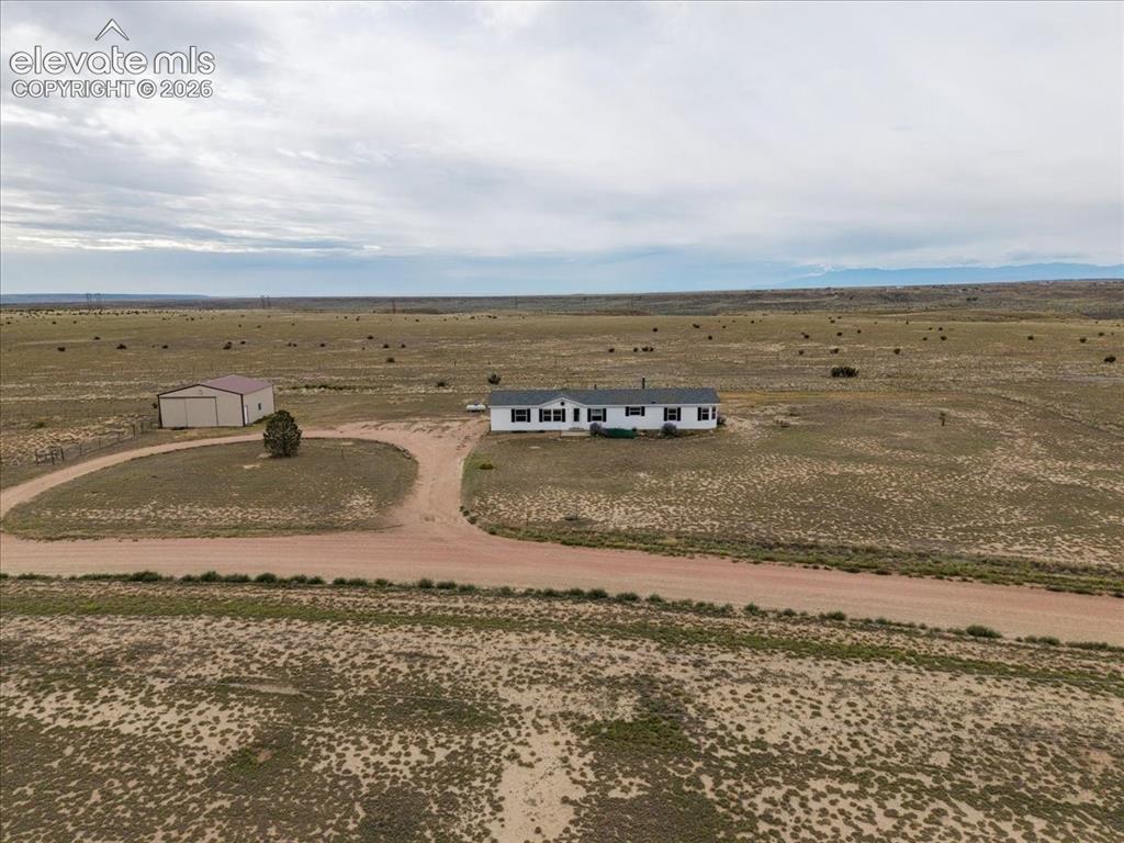 Image 21 of 23: Expansive rural property featuring a white residence with dark shutters, a
