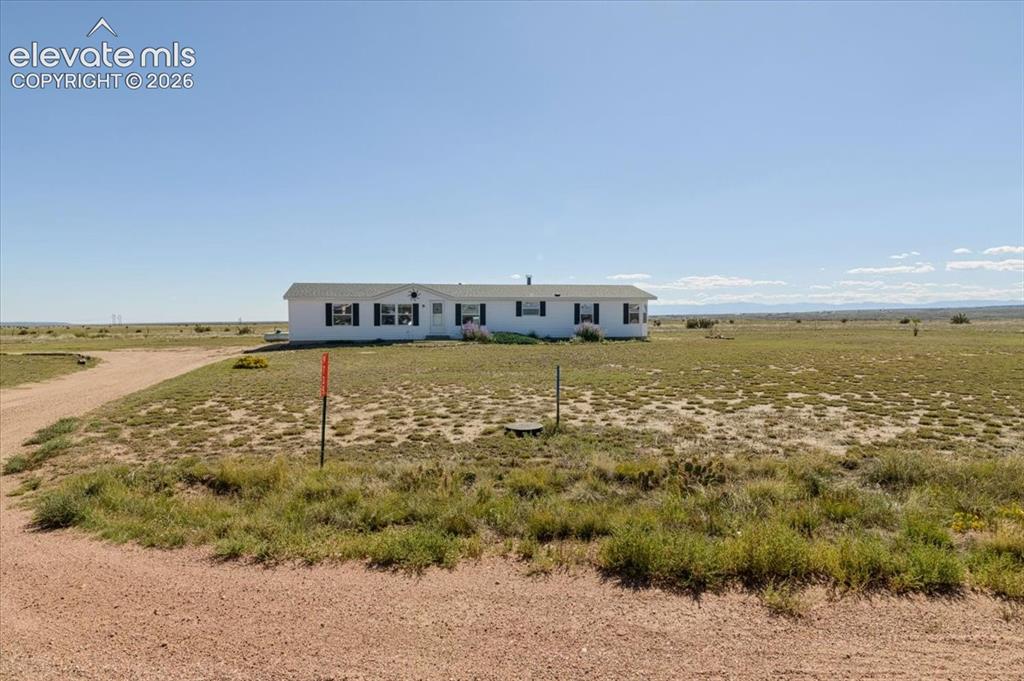 Image 21 of 25: White single-story residence with a light-colored roof, multiple windows wi
