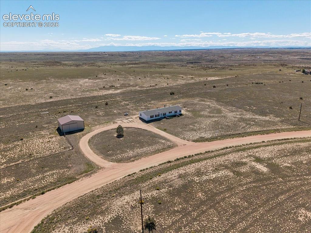 Image 23 of 25: Extensive open acreage with a primary residence, a large outbuilding, and a