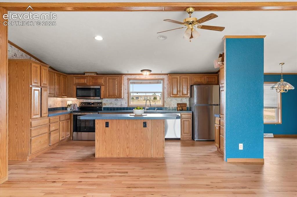 Image 4 of 23: Kitchen featuring wood-finish cabinetry, stainless steel appliances, blue c