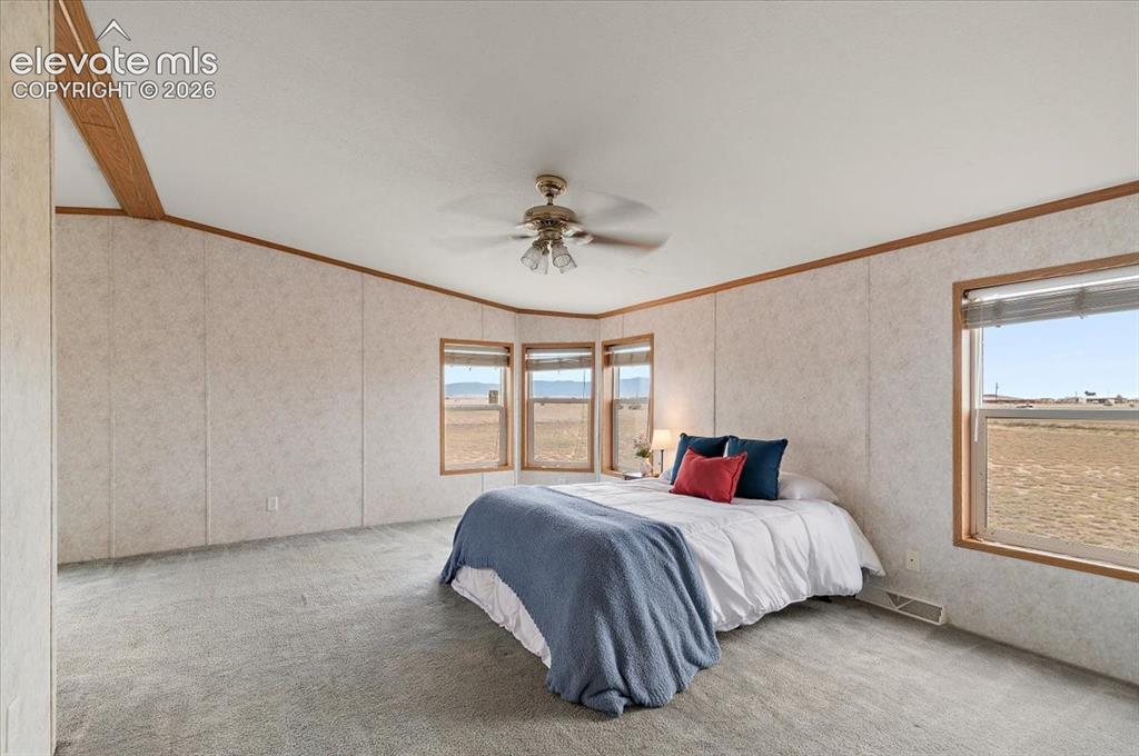 Image 7 of 23: Spacious room featuring carpeting, bay windows, a ceiling fan, and multiple