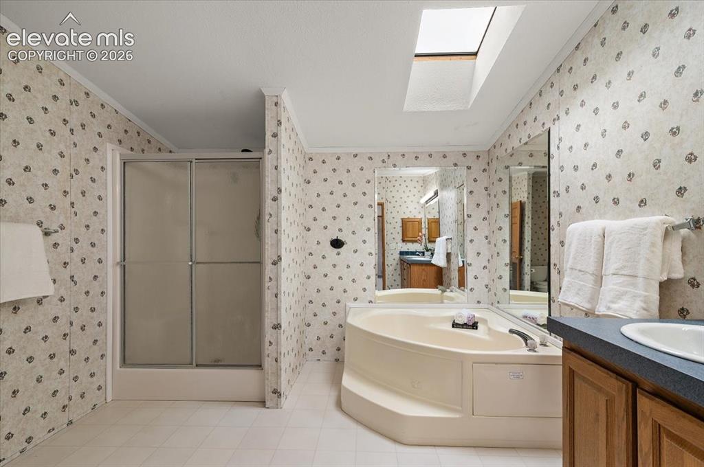 Image 9 of 23: Corner soaking tub, skylight, walk-in shower with sliding frosted doors, fu