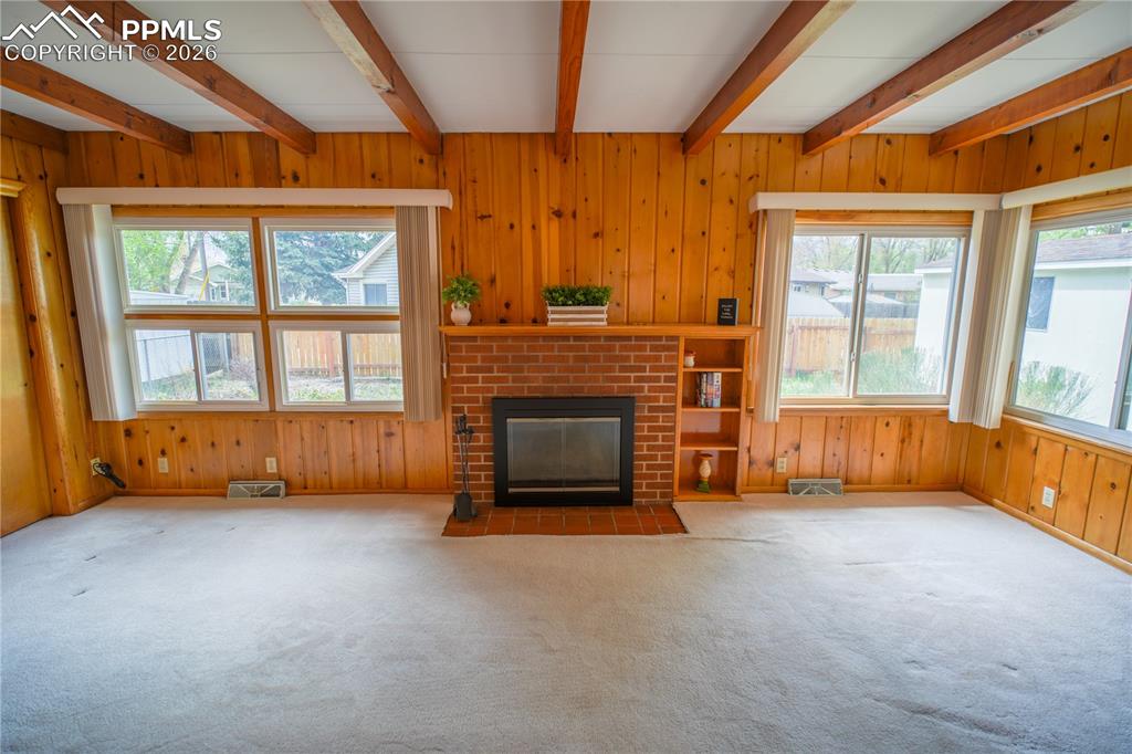 Image 16 of 28: Wonderful knotty pine paneling, an abundance of natural light, and a brick 