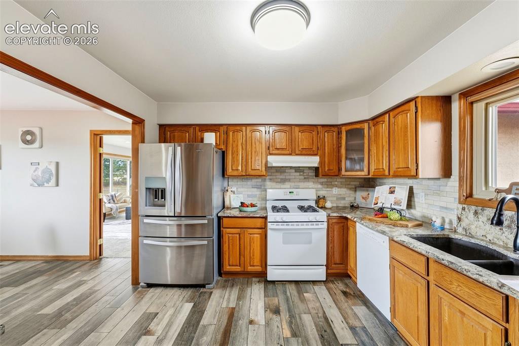 Image 11 of 50: Wood-finish flooring, wood cabinetry, stone countertops, stainless steel re