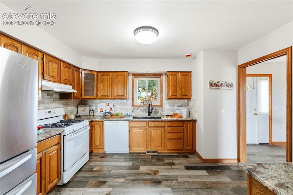 Image 12 of 50: Kitchen featuring wood-finish flooring, wood cabinetry, granite-style count