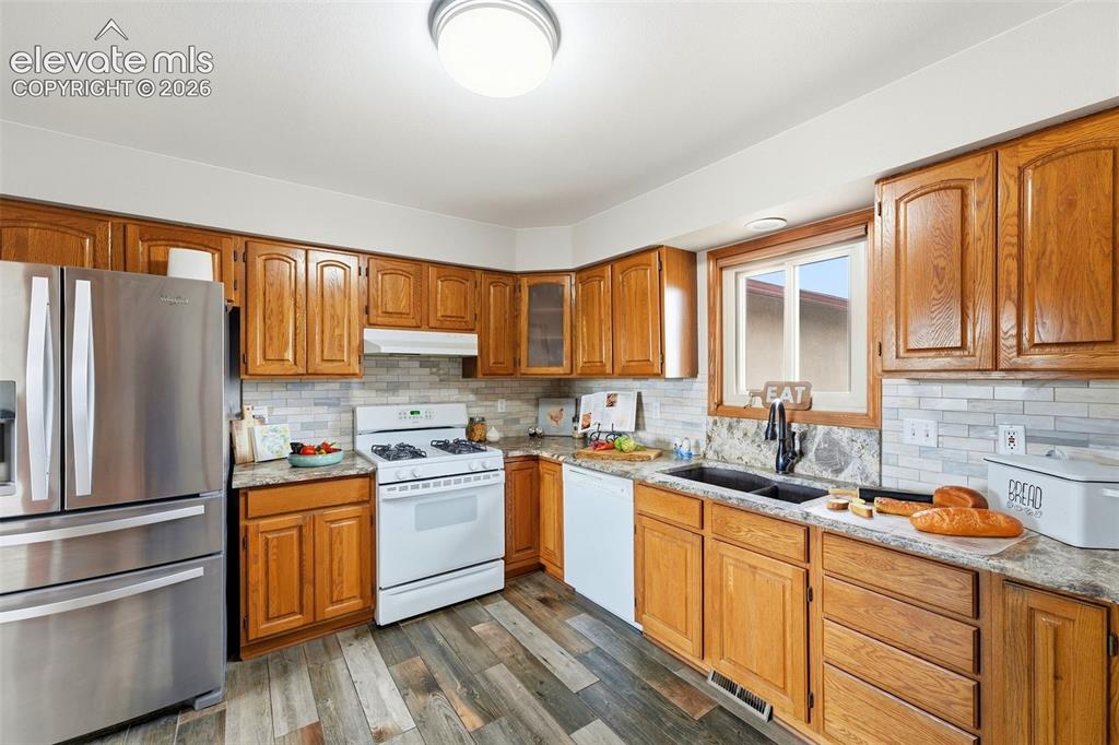 Image 13 of 50: Kitchen featuring wood cabinetry, stainless steel refrigerator, white gas r
