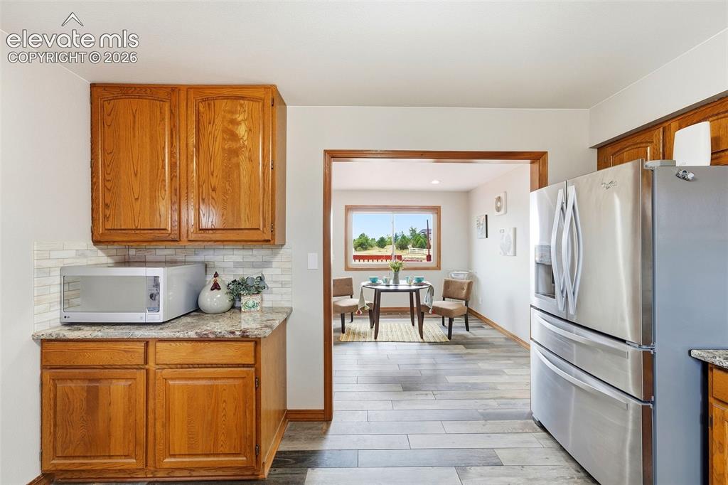 Image 14 of 50: Wood-finish flooring, wood cabinetry, stone-finish countertops, and a white