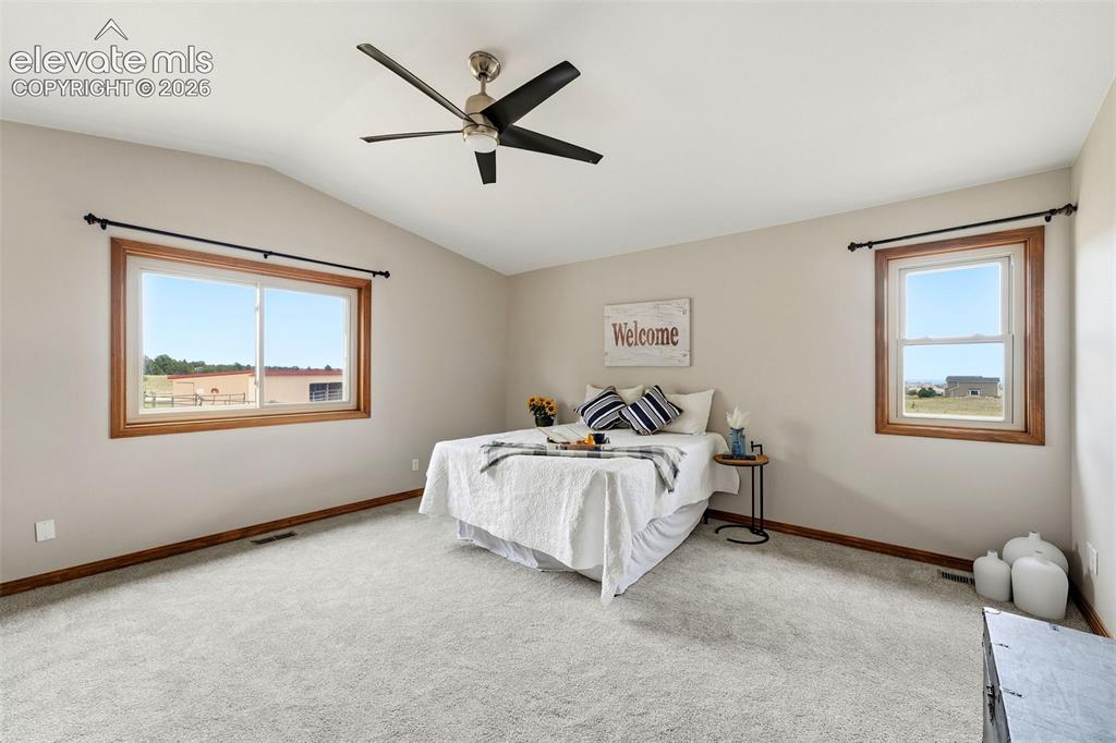 Image 22 of 50: Vaulted ceiling with a ceiling fan, light-colored carpeting, and light-tone
