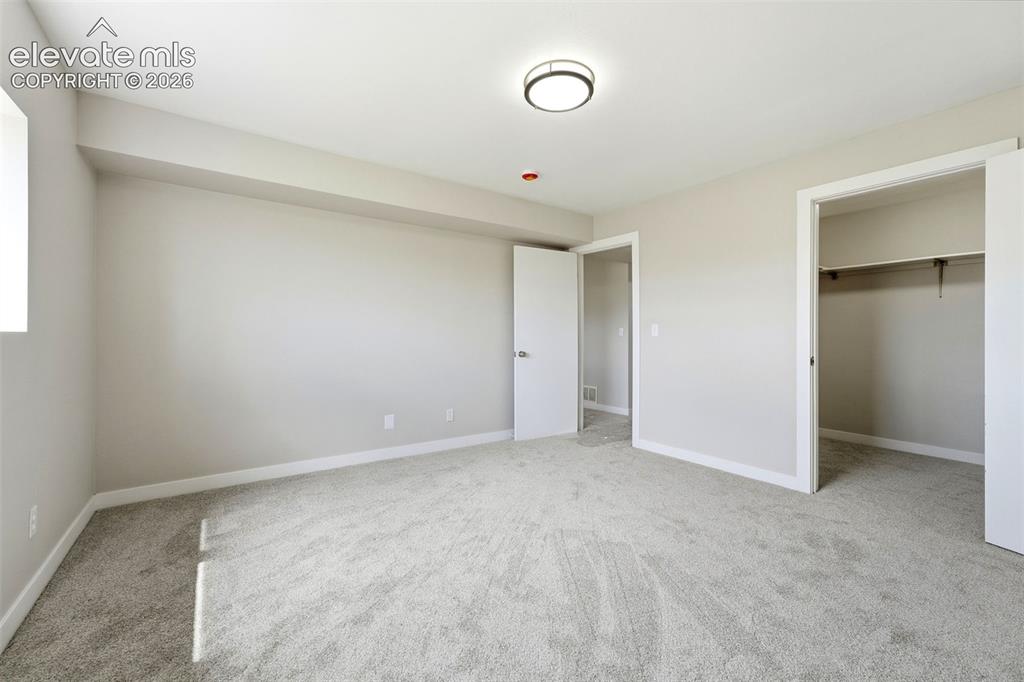 Image 25 of 50: Neutral-toned walls with light gray carpeting, featuring a modern flush-mou