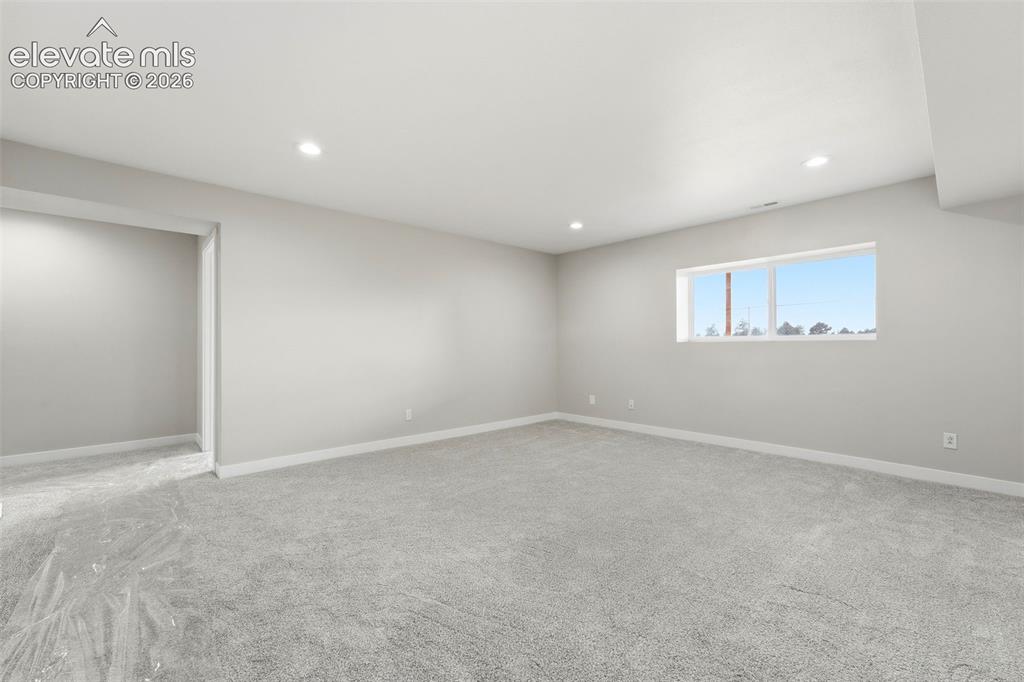 Image 27 of 50: Recessed lighting illuminates the neutral-toned walls and soft gray carpeti