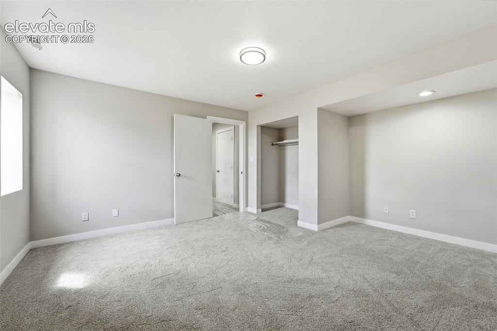 Image 29 of 50: Soft gray wall paint with light gray carpeting, featuring an open closet wi