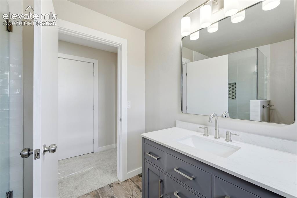 Image 30 of 50: Vanity with a white countertop and undermount sink, wood-finish flooring, a