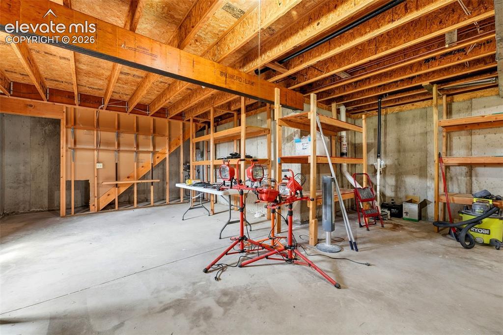 Image 32 of 50: Unfinished basement space with exposed concrete walls, exposed ceiling jois