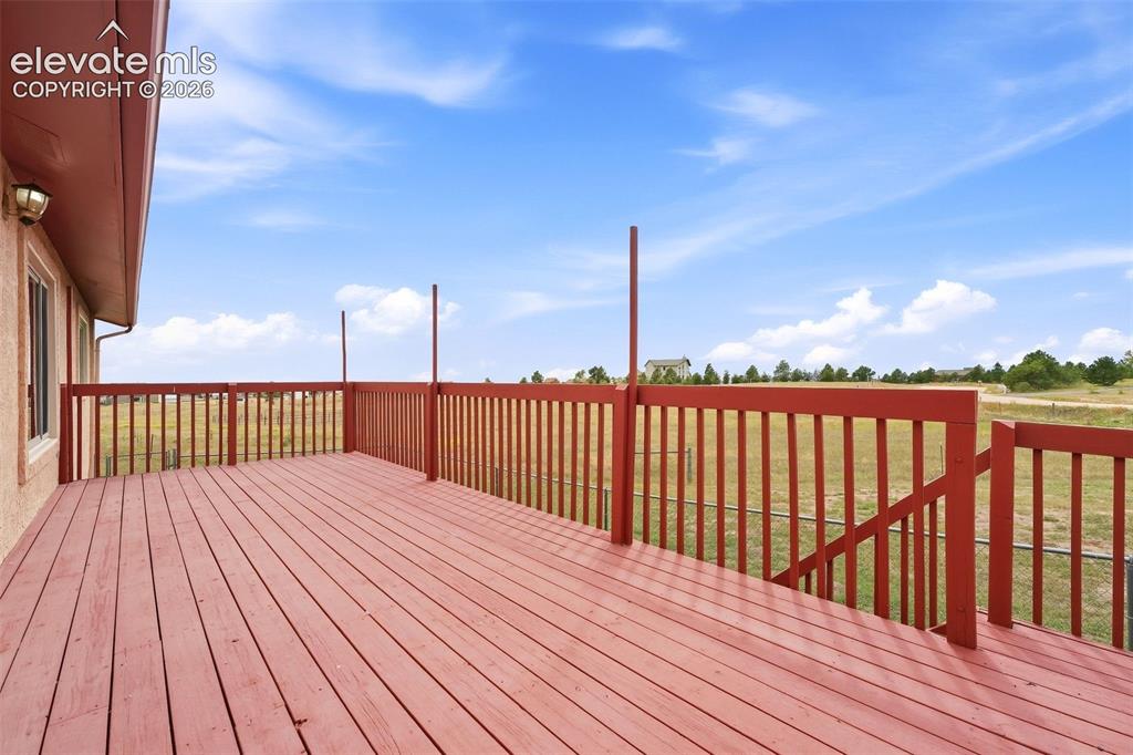 Image 34 of 50: Expansive wood deck with a red finish, full perimeter railing, and integrat
