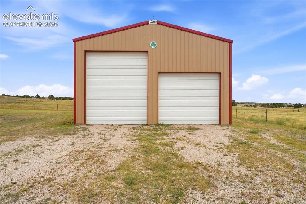 Image 41 of 50: Metal-sided outbuilding with a two-bay design, featuring a larger and small