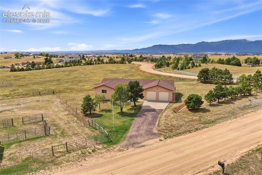 Image 46 of 50: Expansive lot with a ranch-style home featuring an attached two-car garage,